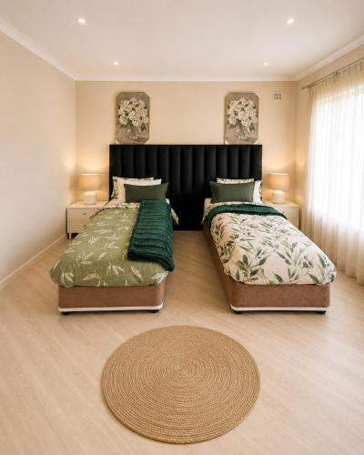 a bedroom with two beds and a rug at The Luxury Orchid in Pietermaritzburg