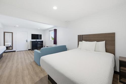 a hotel room with a large bed and a blue chair at Hyland Inn Van Nuys in Van Nuys