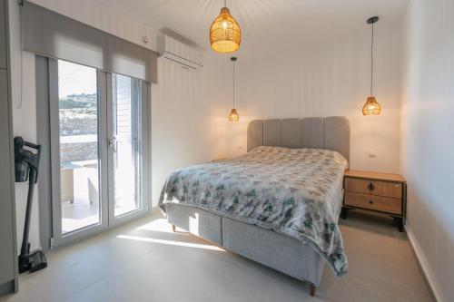 a bedroom with a bed and a large window at Vigla View Sifnos in Vathi