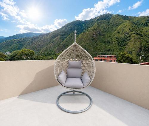 a rattan chair sitting on a balcony with a mountain at Luxury Penthouse with Jacuzzy 6 bedroom in Baños