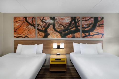 two beds in a hotel room with a painting on the wall at Days Inn by Wyndham Greeneville in Greeneville
