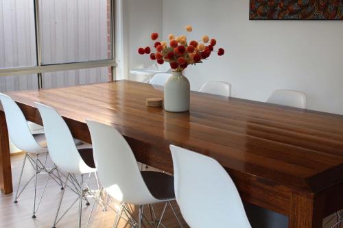 a large wooden table with white chairs and a vase with flowers at Sunbury on the Park in Sunbury