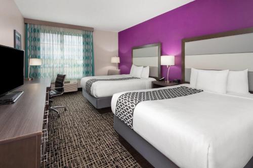 a hotel room with two beds and a flat screen tv at La Quinta by Wyndham Springfield IL in Springfield
