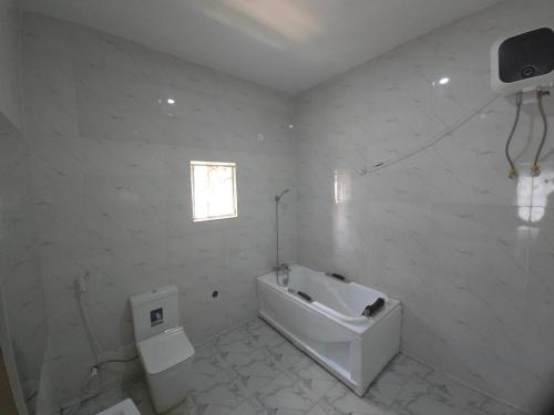a white bathroom with a tub and a toilet at House 27 Cool vibes in Idu