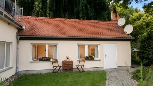a small white house with two chairs in the yard at Ferienwohnung Hoffmann in Radebeul