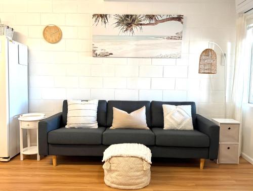 a living room with a blue couch with pillows at Family & Couples Beachside Stay Ocean Glimpses 7 day Xmas 2026 available in Brooms Head