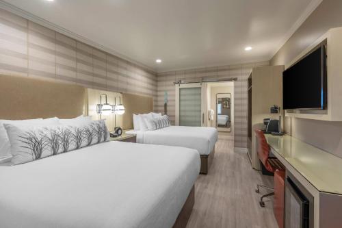 a hotel room with two beds and a flat screen tv at Bluestem Hotel Torrance Los Angeles, an Ascend Collection Hotel in Torrance
