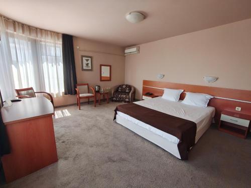 a hotel room with a large bed and a desk at Семеен хотел"Свети Георги" in Burgas