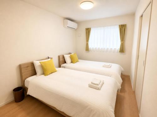 two beds in a small room with yellow pillows at Nakijin Terrace in Nakijin