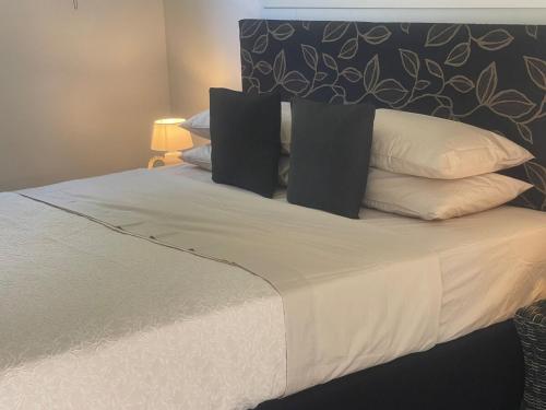 a bed with black and white pillows on it at Studio self-contained and recently renovated in Avarua