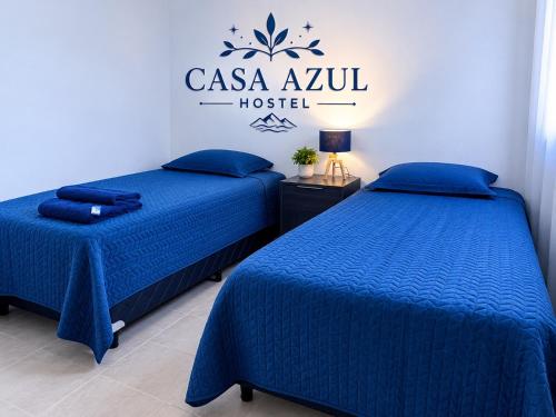 two beds in a room with a hotel sign on the wall at Casa Azul in La Quiaca