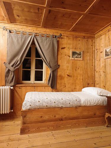 a bed in a wooden room with a window at Locanda Teggiate in Madesimo