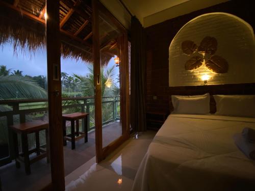 a bedroom with a bed and a view of a balcony at Dira Bungalows in Tetebatu