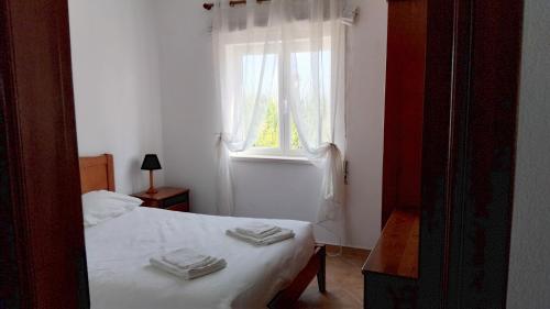 a bedroom with a bed and a window with towels on it at CCCA Monte Loureiro in Raposeira