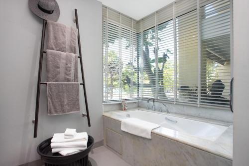 a white bathroom with a tub and a window at Karon Beach Stunning 2 bed apt unit 700 in Karon Beach