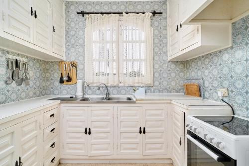 a kitchen with white cabinets and a sink and a window at Villa en Capistrano V. 4 a 9 plazas in Nerja