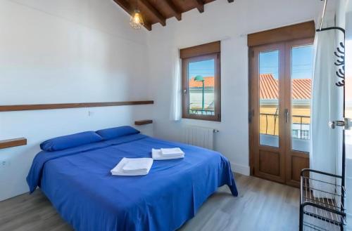 a bedroom with a blue bed and a window at EL RINCÓN DE DENVER in Suances