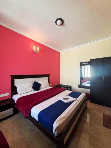 a bedroom with a large bed with a red wall at IMPERIAL COTTAGE, HILL BUNK OOTY in Ooty