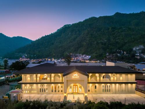 a large building with lights on in front of a mountain at Moustache Select Rishikesh Mohanchatti in Mohan Chatti