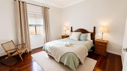a bedroom with a bed and a chair and a window at Sals Cottage in Busselton