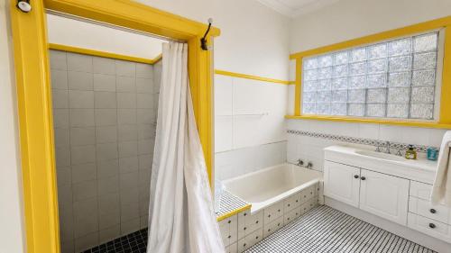 a bathroom with a tub and a shower curtain at Sals Cottage in Busselton