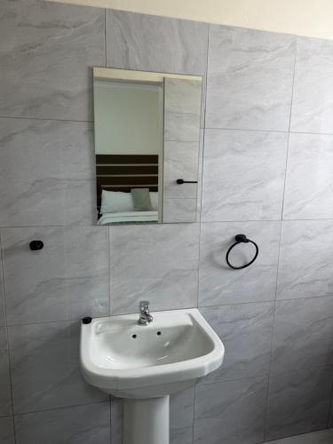 a white bathroom with a sink and a mirror at Coastwave Guesthouse CBD in Walvis Bay