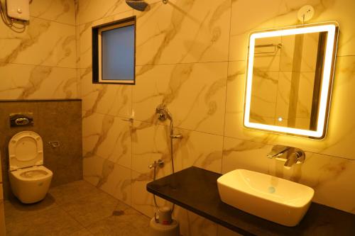 a bathroom with a sink and a toilet and a mirror at Hotel river view sringeri in Sringeri