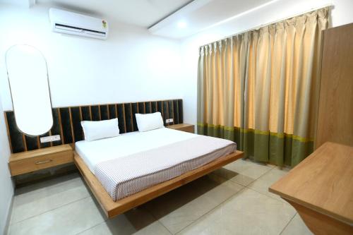 a bedroom with a bed and a desk and curtains at K D Motels in Patiāla