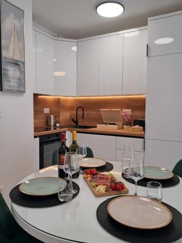 a table with wine glasses and a plate of food at Luxury Mint Garden Apartment in Kaštela