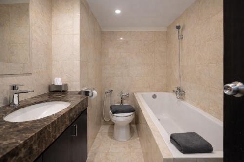 a bathroom with a tub and a toilet and a sink at The Mirah Hotel Bogor in Bogor