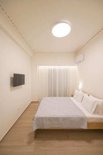 a white bedroom with a large bed and a television at Corali 1 - Coastal Retreat in Katakolo