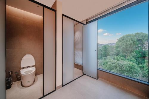 a bathroom with a toilet and a large window at Zhangjiajie The Brookside Hotel& Tianmen National Forest Park & Free pick up service in Zhangjiajie
