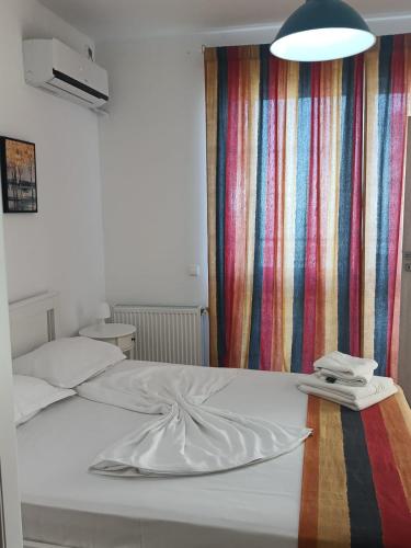 a white bed in a room with a striped curtain at Sea View 3-Room Apartment in Olimp