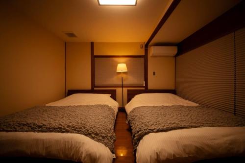 a bedroom with two beds and a lamp in it at GENPEI Guest House in Takamatsu