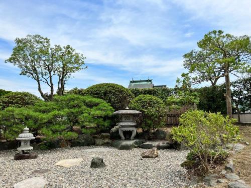a garden with a fountain and trees and a building at GENPEI Guest House in Takamatsu
