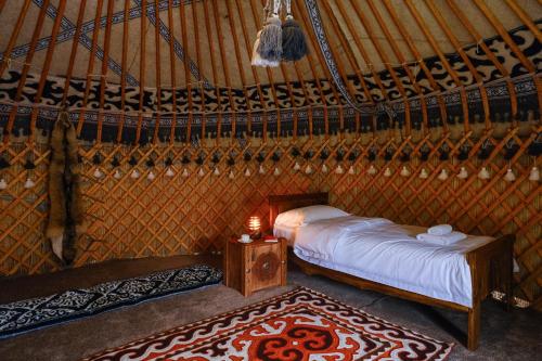 a bedroom in a yurt with a bed and a rug at Kurjun Guest House in Bokonbayevo
