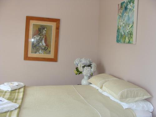 a bedroom with a bed and a vase of flowers at Oamaru Pink Cottage in Oamaru