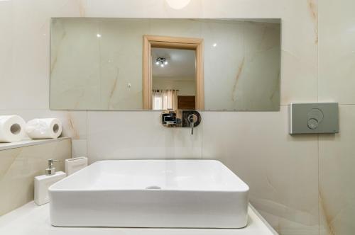 a white bathroom with a sink and a mirror at Kripis Studio in Pefkochori