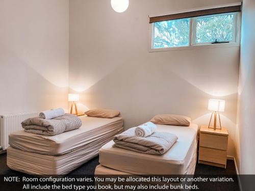 two twin beds in a room with a window at Ajax Ski Club in Mount Buller