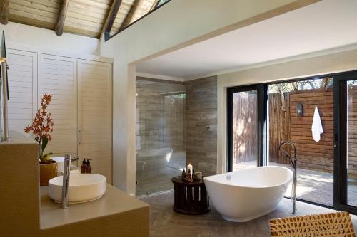 a bathroom with two sinks and a tub and a shower at Lion Sands River Lodge in Sabi Sand Game Reserve
