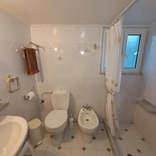 a white bathroom with a toilet and a sink at Chios Studios Kalamari in Vrontádos
