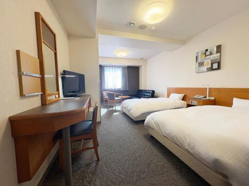 a hotel room with two beds and a desk at Hotel Route-Inn Niihama in Niihama