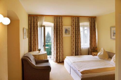 a bedroom with a bed and a chair and a window at Petersenhof in Millstatt