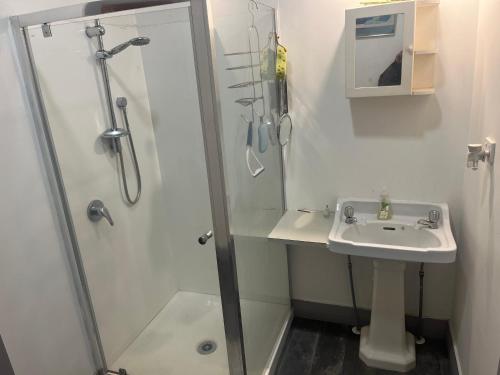 a white bathroom with a sink and a shower at Sullivans backpackers in Waimate