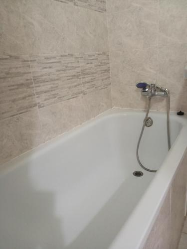 a white bath tub with a shower in a bathroom at Циолковского с кодовым замком in Oral