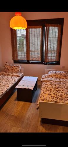 a room with two beds and a table and windows at Makedonium 1 in Struga