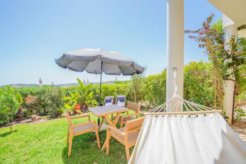 a patio with a table and chairs and an umbrella at Villa Sunrise by MOJE Holiday in Budens