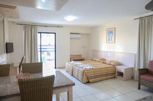 ein Hotelzimmer mit Bett, Tisch und Stühlen in der Unterkunft Senator Hotel Apartments - Adults Only in Ayia Napa