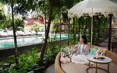 a woman sitting in a chair next to a pool at Indochine Serenity Boutique in Siem Reap