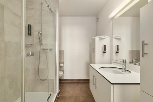 a white bathroom with a sink and a shower at Neuchâtel City Hôtel - Self Check-In in Neuchâtel